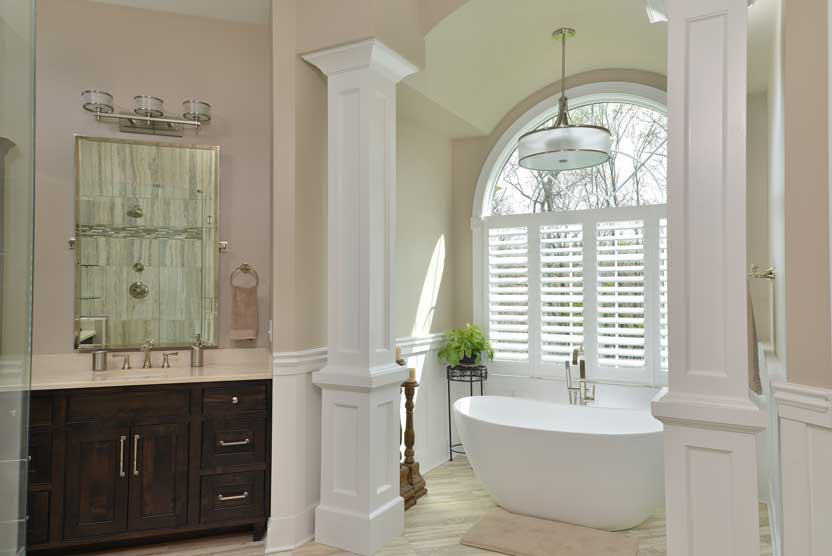 Master bathroom remodel by Tamer Construction with an arched window and freestanding tub